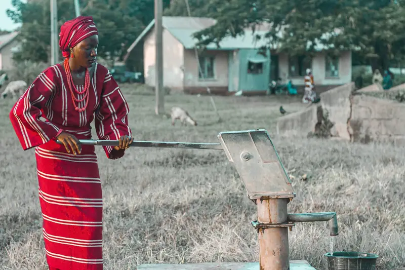 A woman in traditional dress pumping water by hand