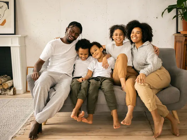 A smiling family of five sitting together on a sofa at home